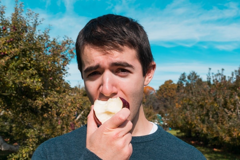 hombre en el bosque comiendo manzana roja