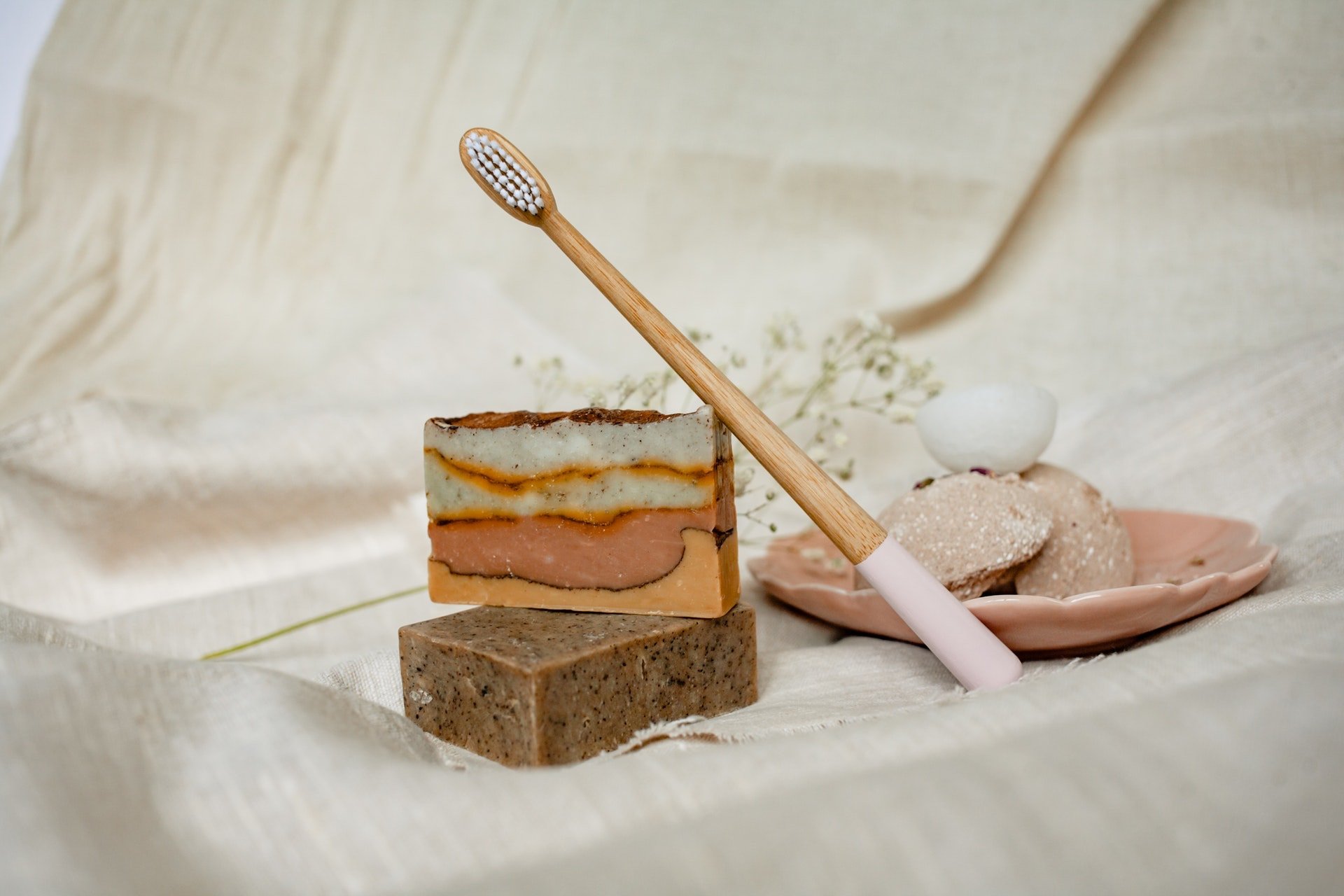 cepillo dental de bambú sostenible con jabones artesanales de color marrón sobre una tela color beige; negocios sostenibles