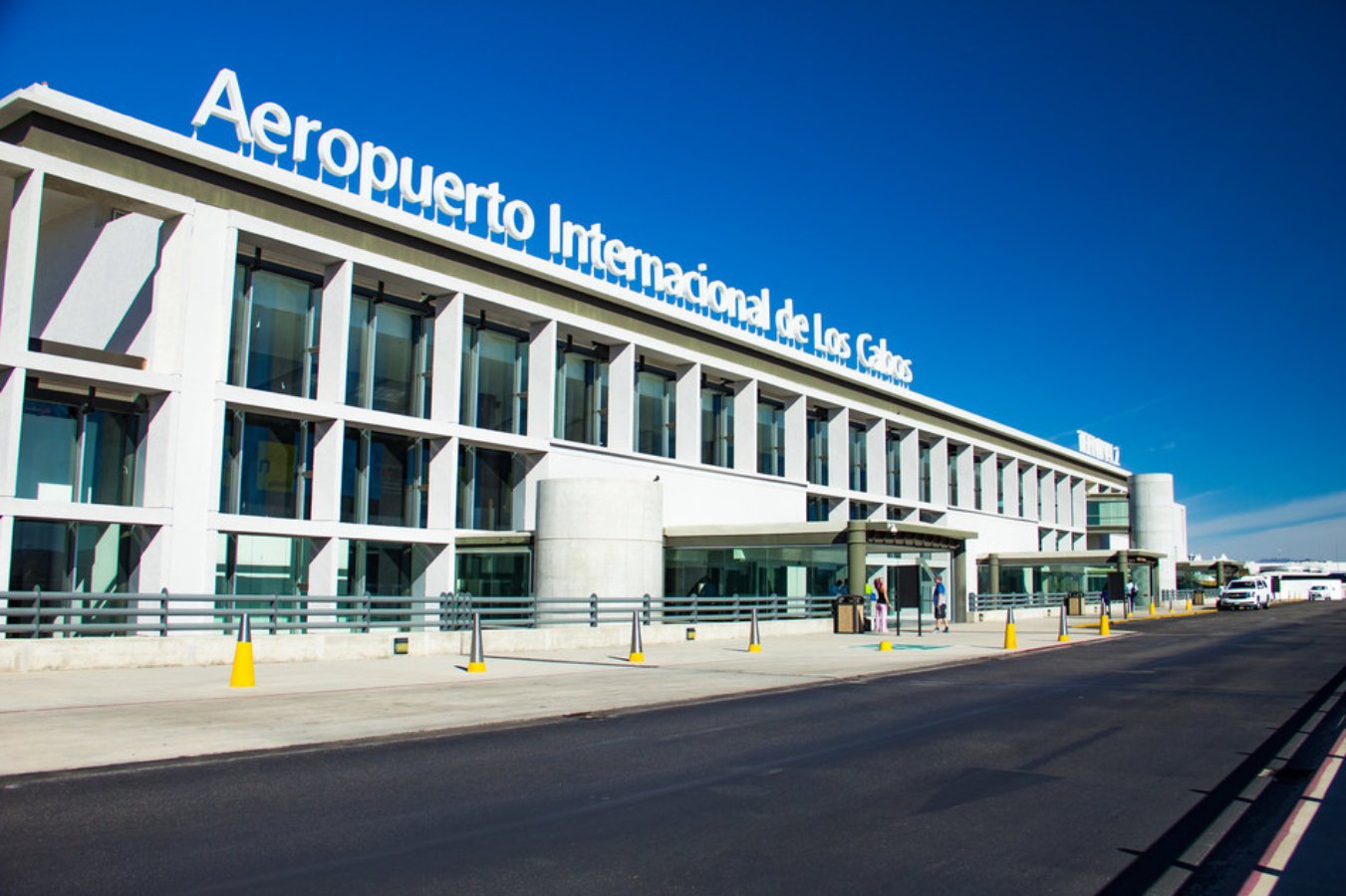 Edificio color blanco con ventanas cuadradas y en la parte de arriba con letras grandes y color blancas "Aeropuerto internacional de los Cabos". Semana Santa