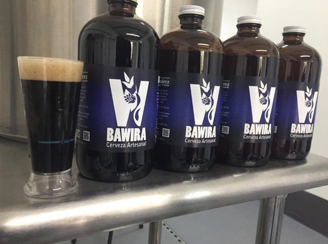 cuatro botellas medianas color ambar con etiqueta color negro con azul y letras color blancas. Cervezas artesanales