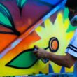 hombre con mascarilla en la cara pintando graffiti de flores de colores
