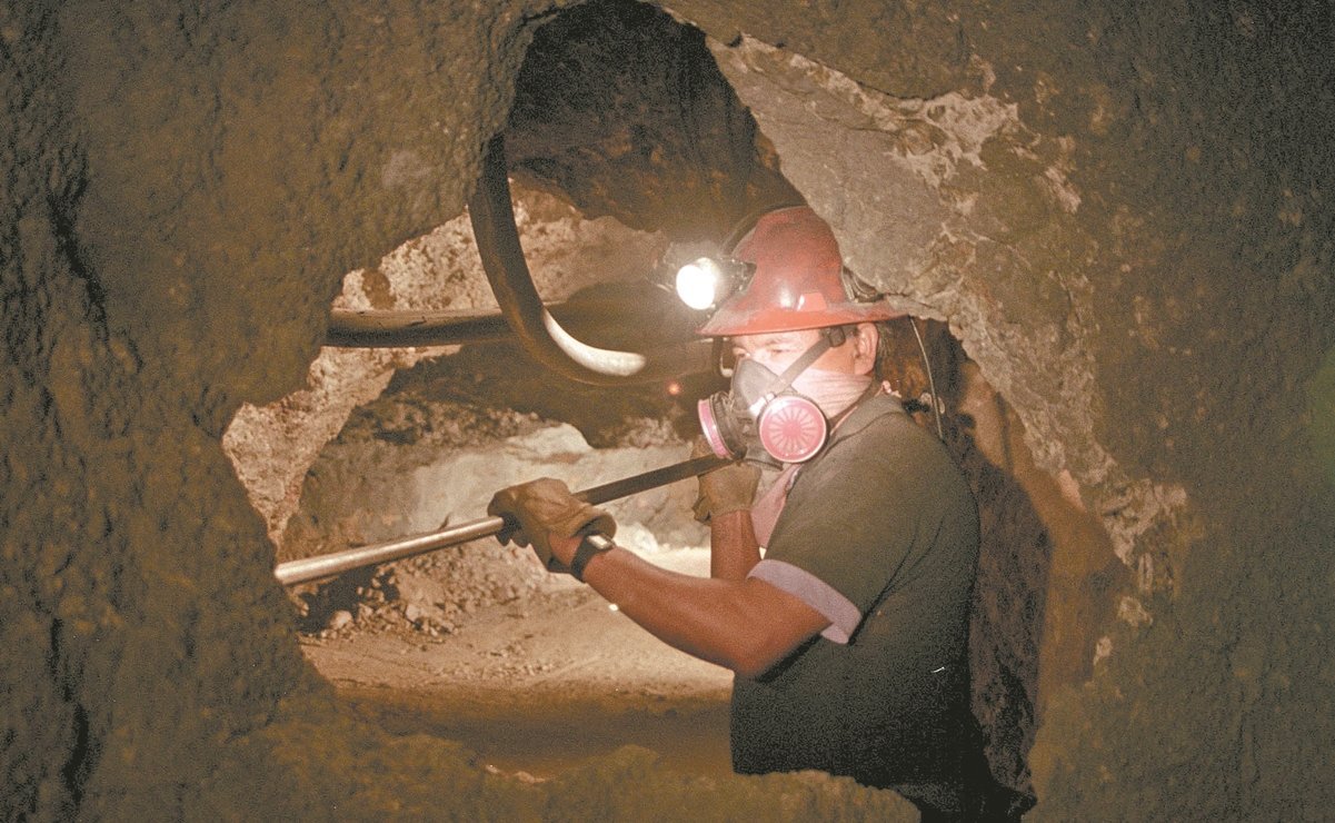 minero con casco naranja y linterna sostiene herramienta con las manos