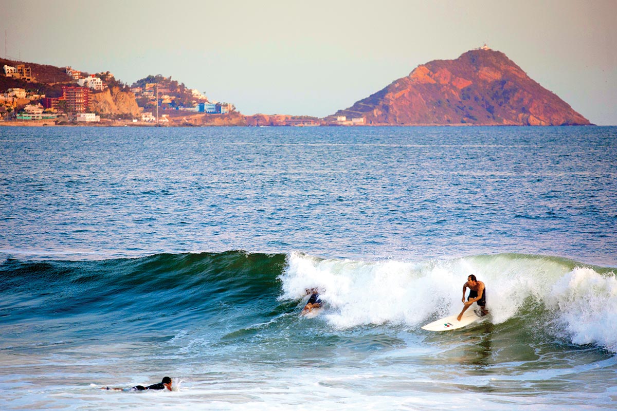 Hombres surfeando en playa de Sinaloa. Semana Santa
