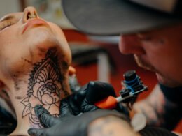 hombre tatuando el cuello de una mujer