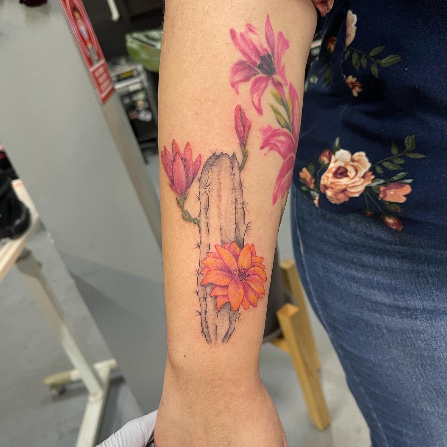 Antebrazo derecho tatuaje de cactus con tinta negra. El cactus tiene flores de color naranja y rosa. Tatuadores de HErmosillo