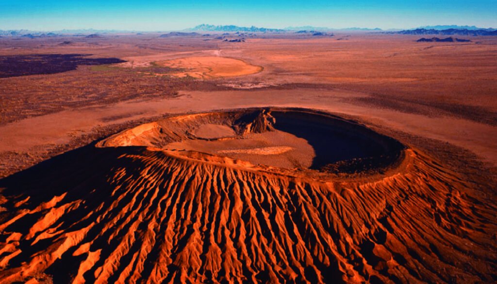 Paisaje del patrimonio de la humanidad El pinacate y gran desierto de altar. Se puede observar un cráter gigante en donde la arena se torna color naranja-rojizo.