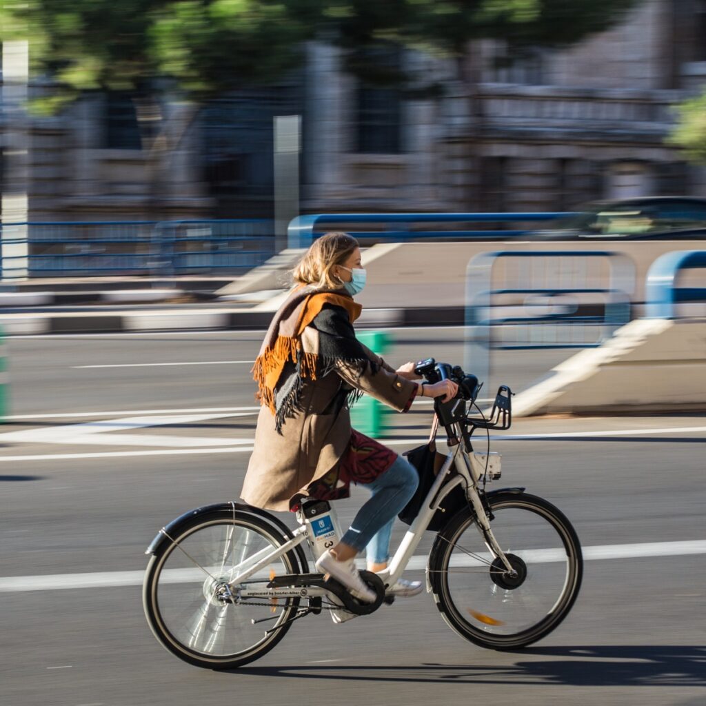 Mujer con abrigo café sobre bicicleta rodando en una calle