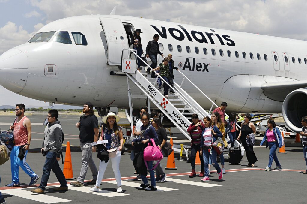 Grupo de personas saliendo del avión de color blanco. Representando el aumento de pasaje aéreo en Mazatlán.