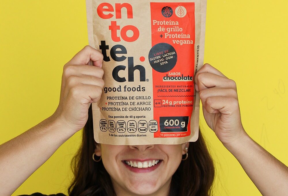 Foto de mujer sonriendo sosteniendo una bolsa de proteína de entotech