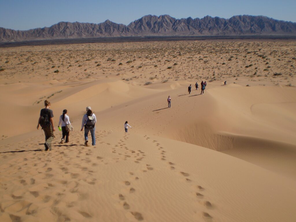 Patrimonio de la humanidad: el gran desierto de altar. Dunas de arena del desierto en donde se puede notar 10 personas caminando en este paisaje.