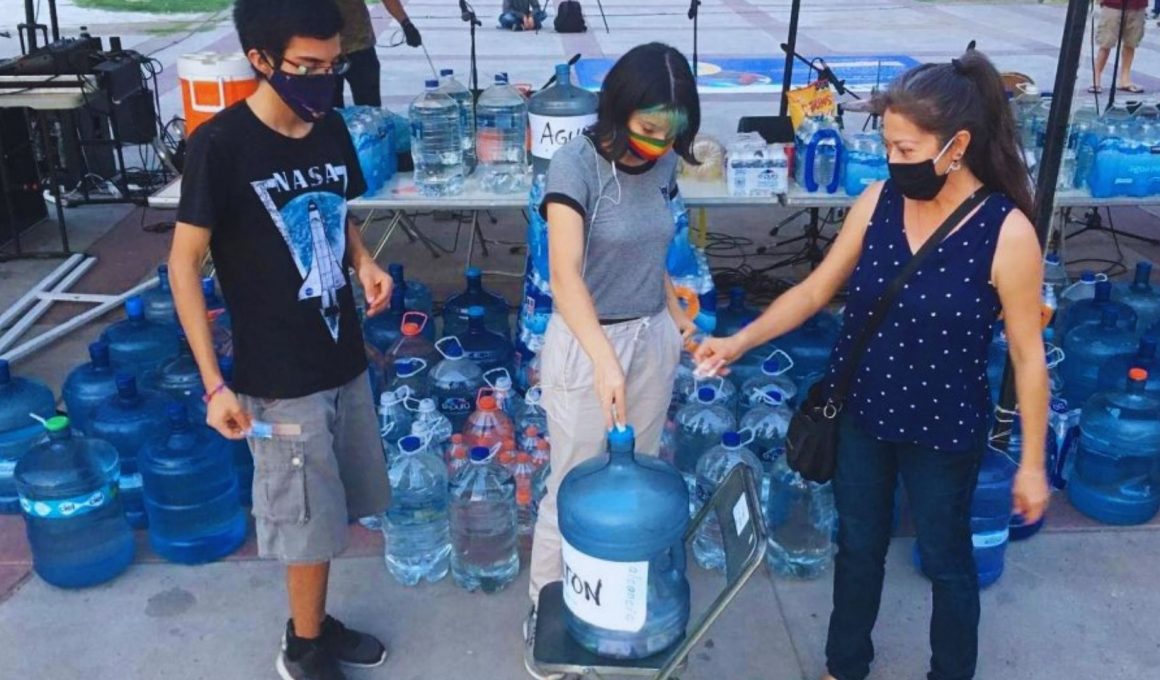 tres personas alrededor de un garrafón de agua en el Aguatón