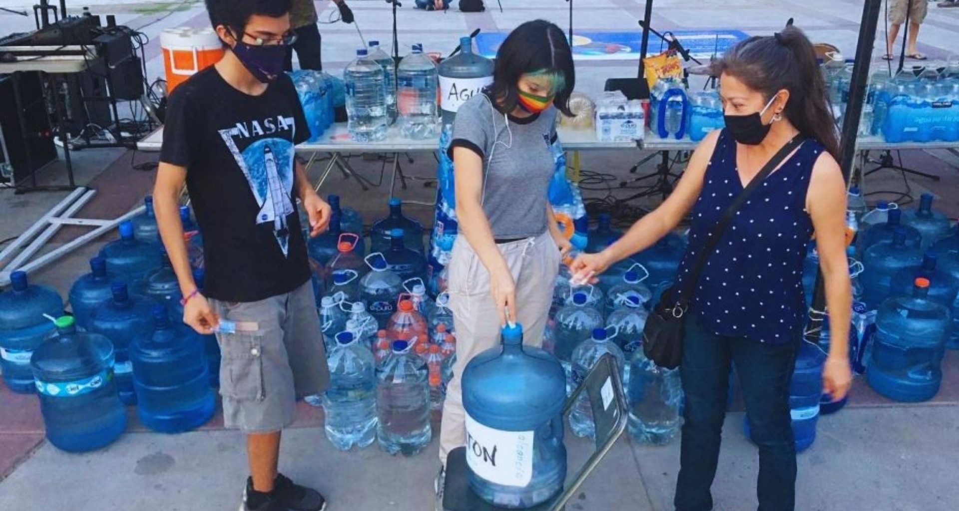 tres personas alrededor de un garrafón de agua en el Aguatón
