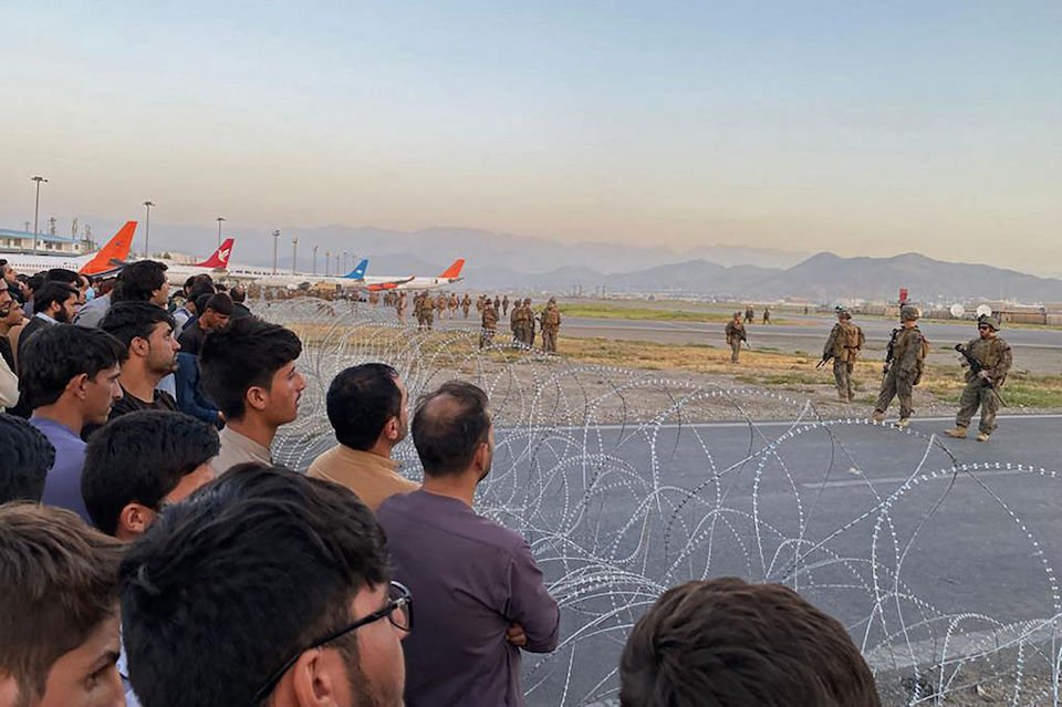 Ciudadanos afganos se agolpan en el aeropuerto mientras soldados estadounidenses montan guardia, en Kabul, el 16 de agosto de 2021.