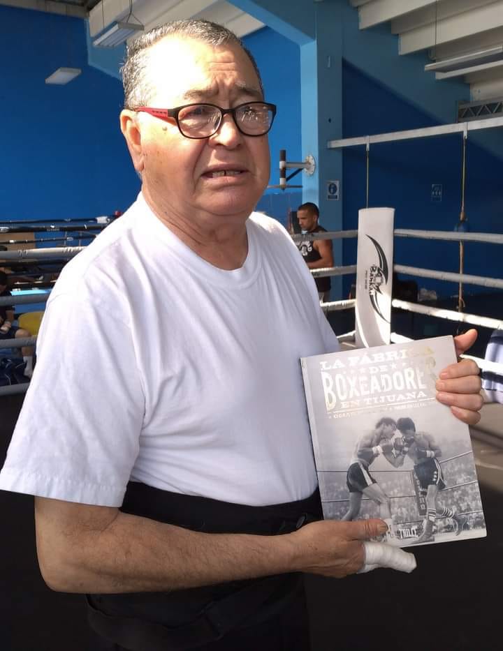 Don Rómulo Quirarte sosteniendo el libro de Omar Millán "La fábrica de boxeadores" en Tijuana.