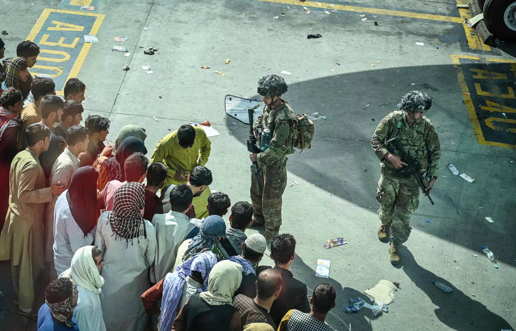 Soldados estadounidenses hacen guardia mientras afganos esperan en el aeropuerto de Kabul el 16 de agosto.