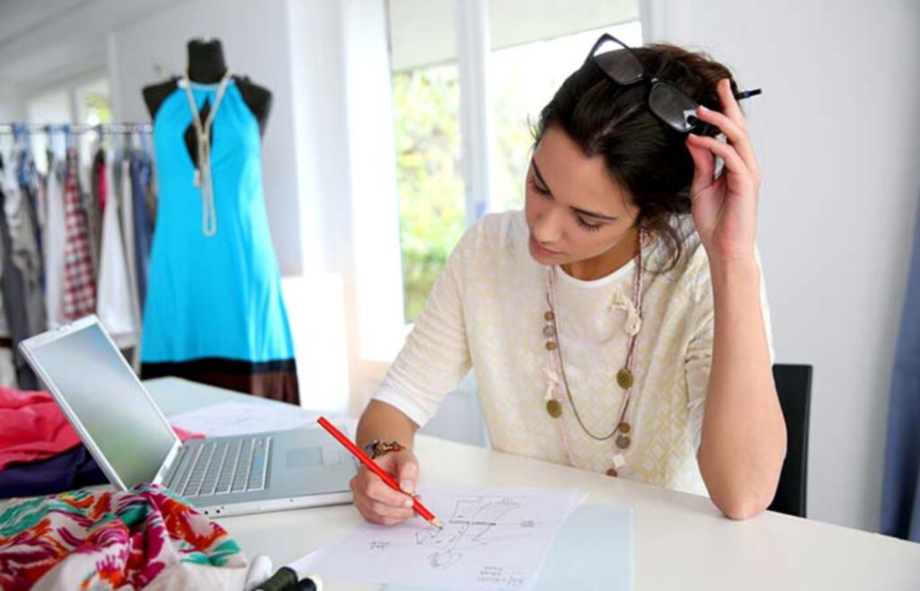 Diseñadora de modas trabaja en un boceto sobre escritorio