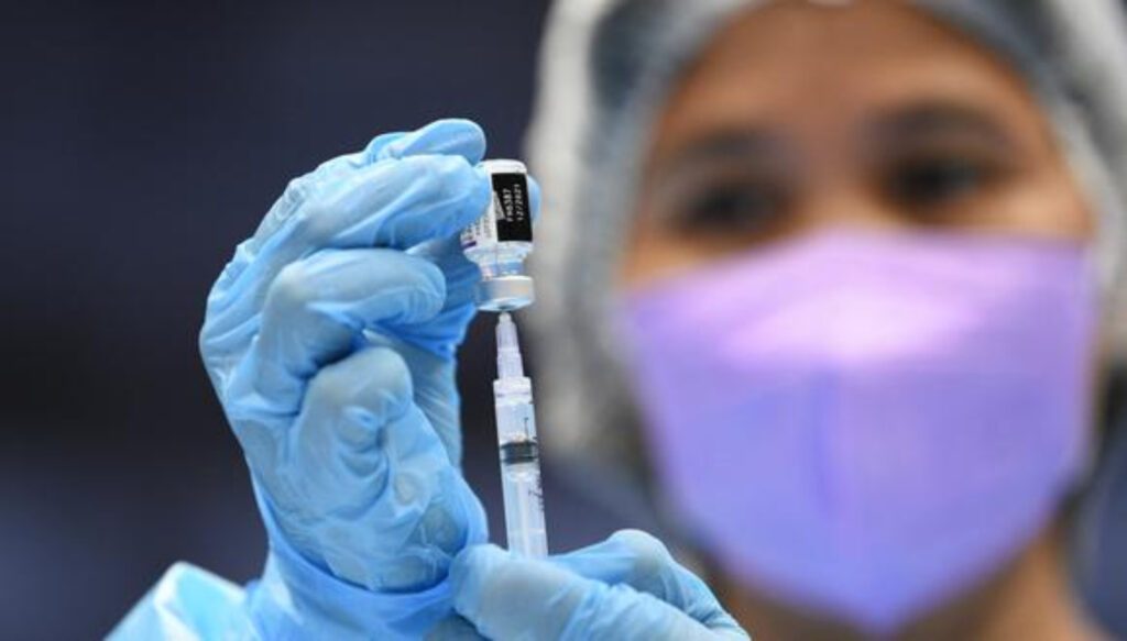 Médica sostiene vial de donde extrae vacuna