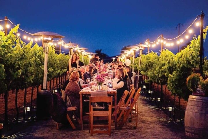 Mesa con familia y amigos durante una cena al anochecer en un vinedo del Valle de Guadalupe en Baja California