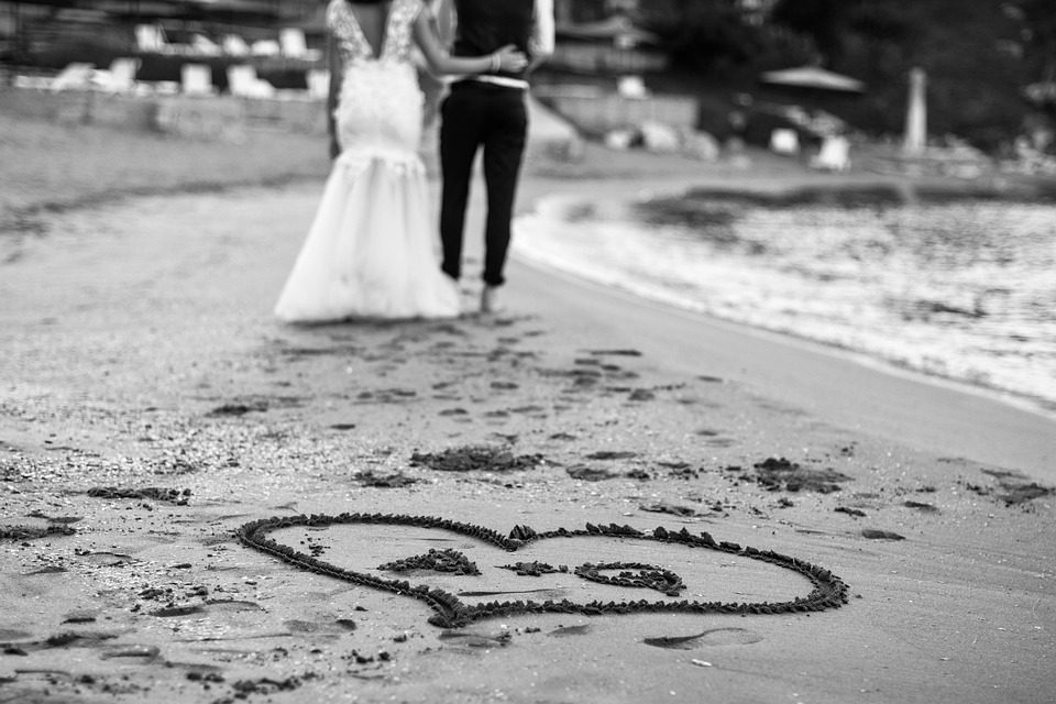 Pareja recien casada caminando en la playa y dibujaron un corazon en la arena