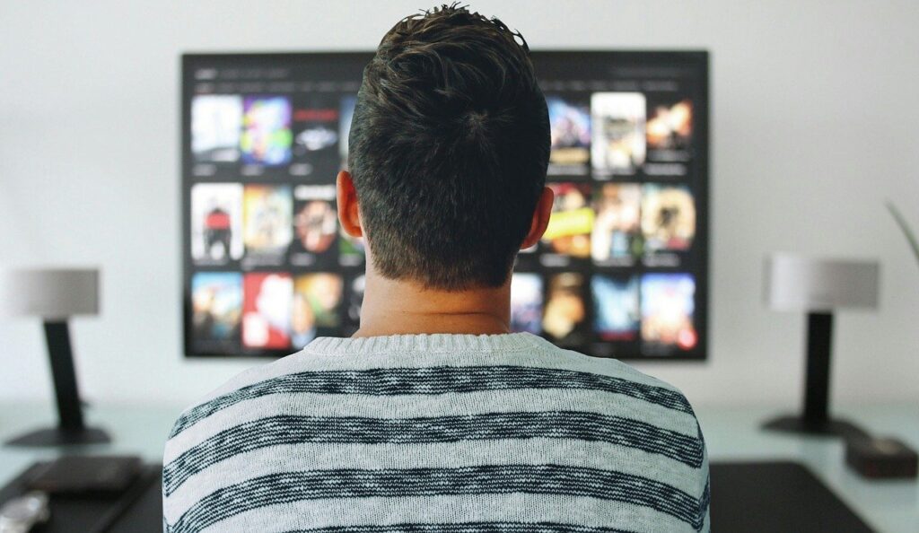 Hombre viendo una serie o pelicula en la television de su casa despues de trabajar. Practicando la desconexion digital