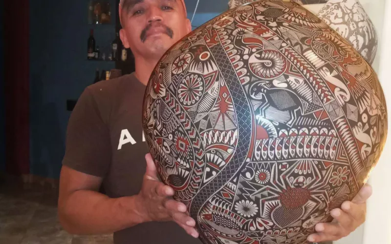 Gregorio Silveira sostiene con sus dos manos la pieza de cerámica que elaboró para el concurso.