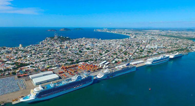 Es la imagen panorámica del puerto de Mazatlán, porque vuelven los cruceros a Sinaloa. Se muestran tres cruceros en fila, a un lado de la costa.