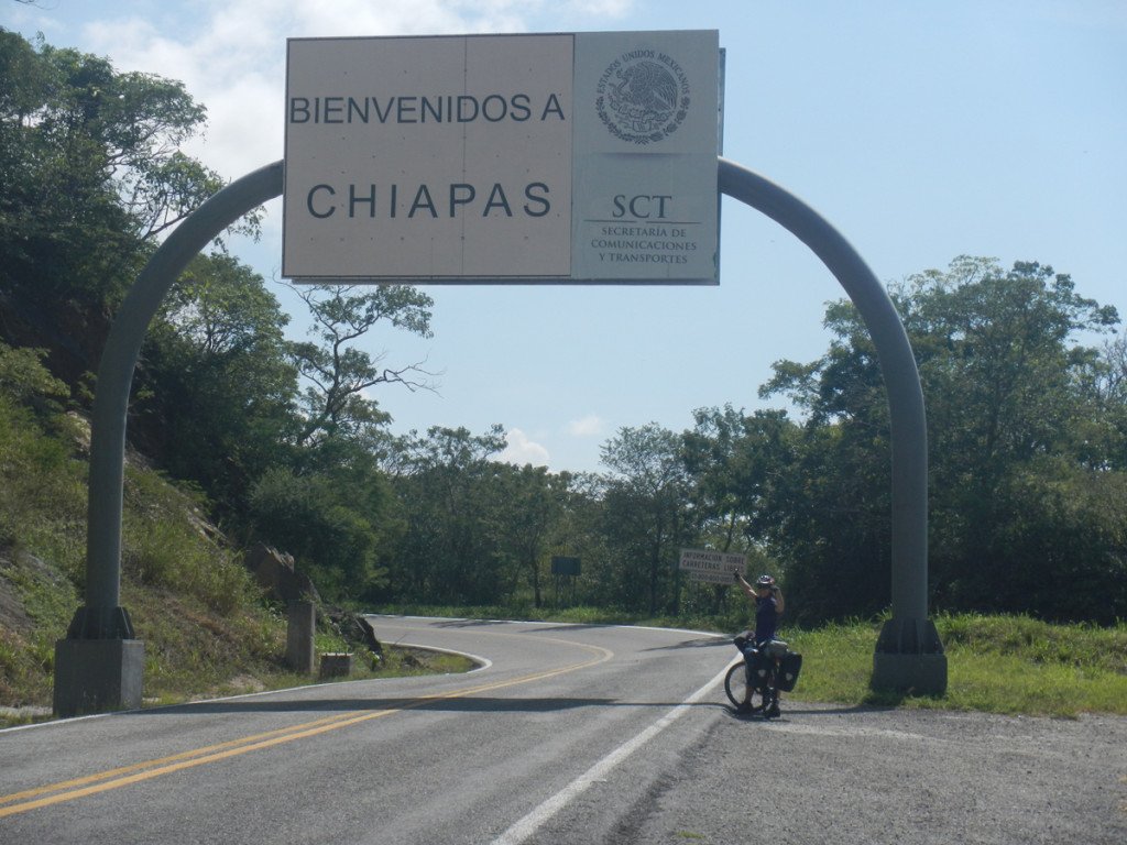 Es una mujer en el letrero de Bienvenidos a Chiapas. Ella es una persona que busca recorrer el país en bicicleta.