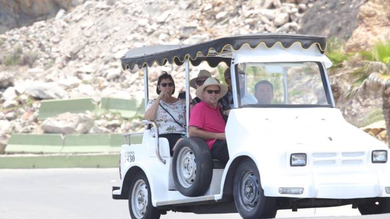 Turistas se desplazan en un carrito de golf blanco.