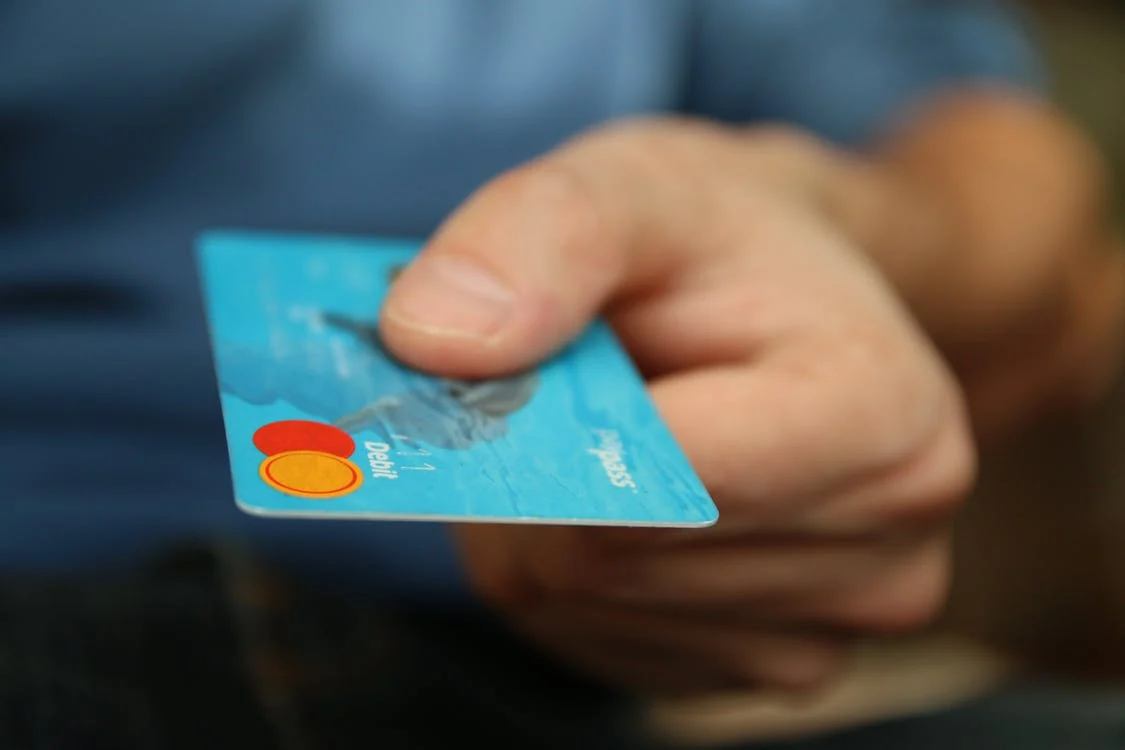 Una persona extiende una tarjeta bancaria azul.