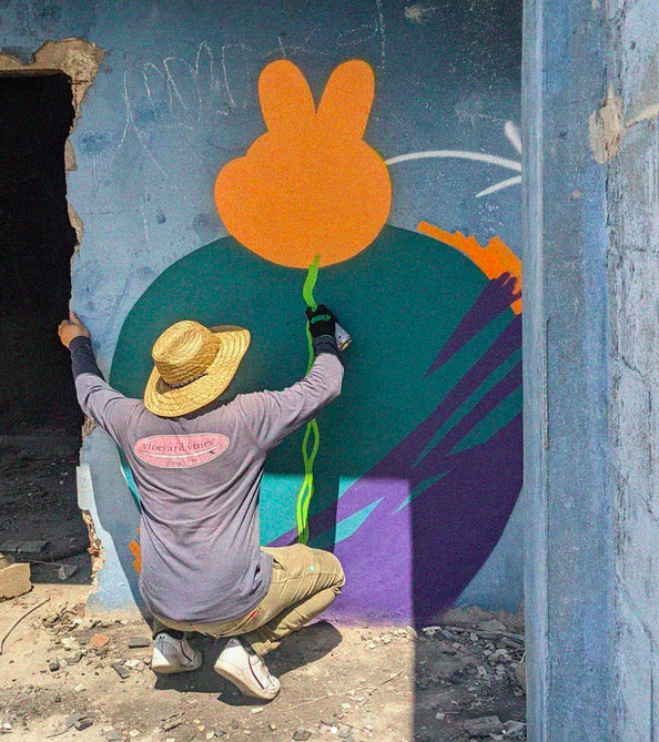 Adrián Orozco de espaldas mientras pinta un mural.