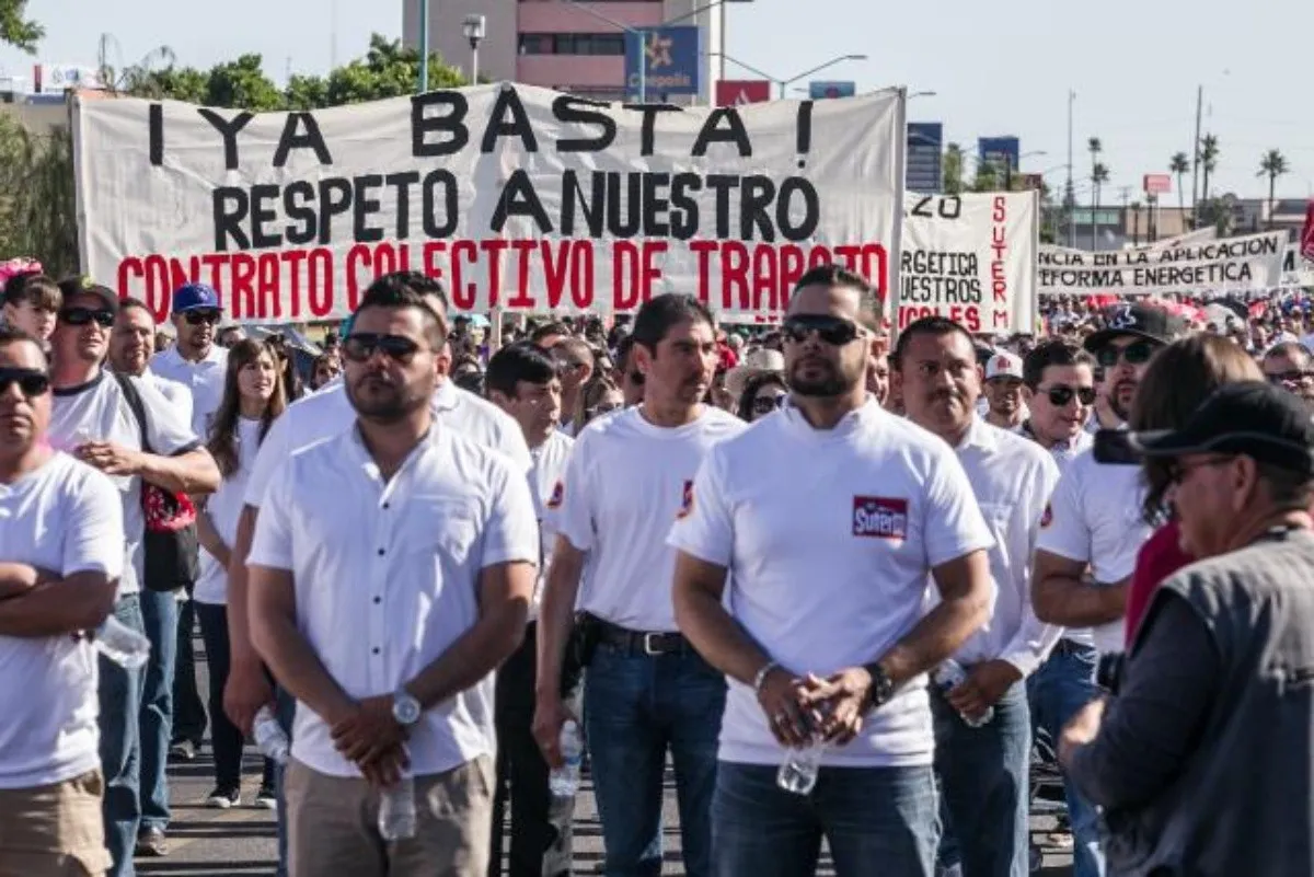 Imagen ilustrativa de trabajadores mexicanos. Es una fotografía de una manifestación durante el día del trabajo. En su mayoría son hombres con camisetas blancas.