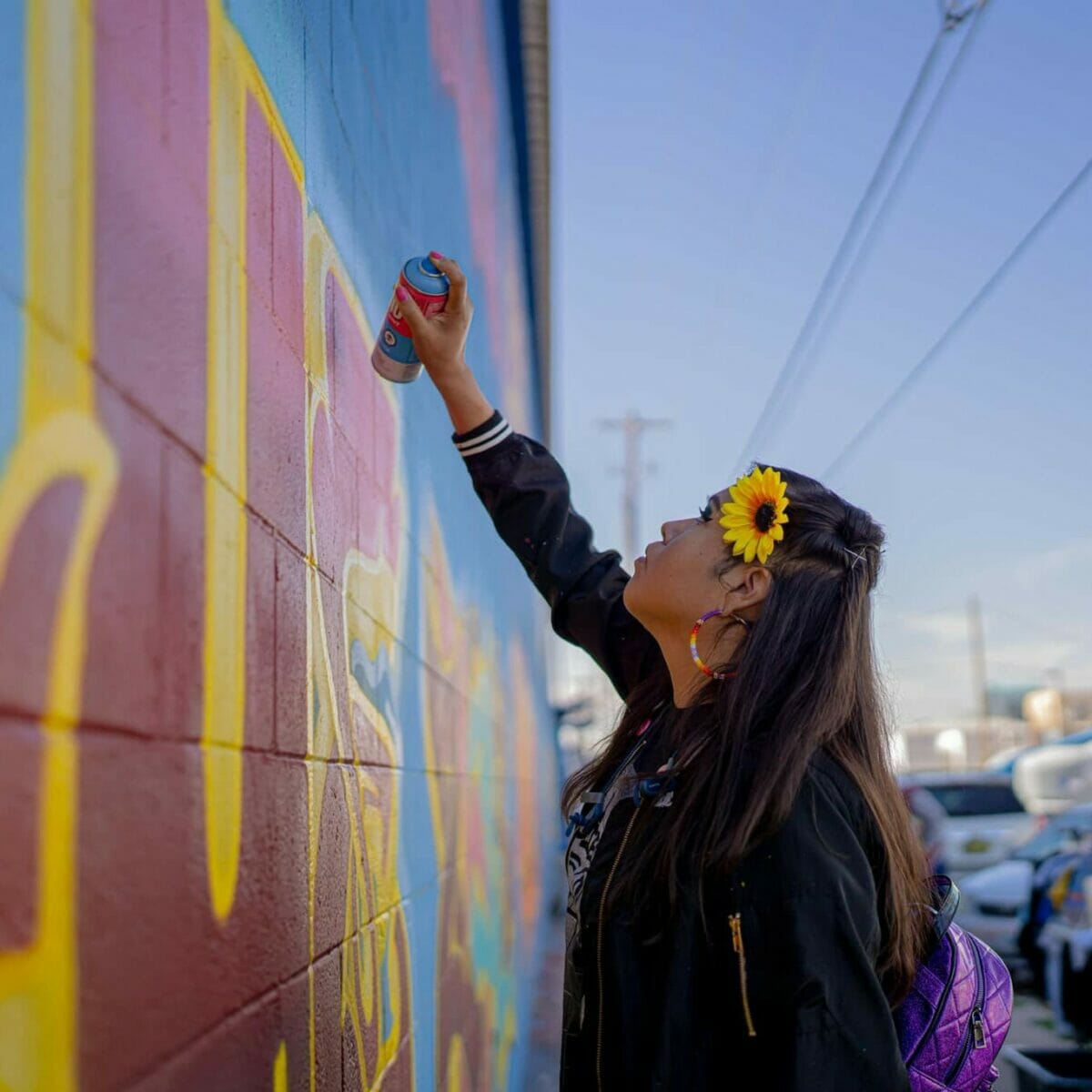 woman paints graffiti on urban art wall in Arizona