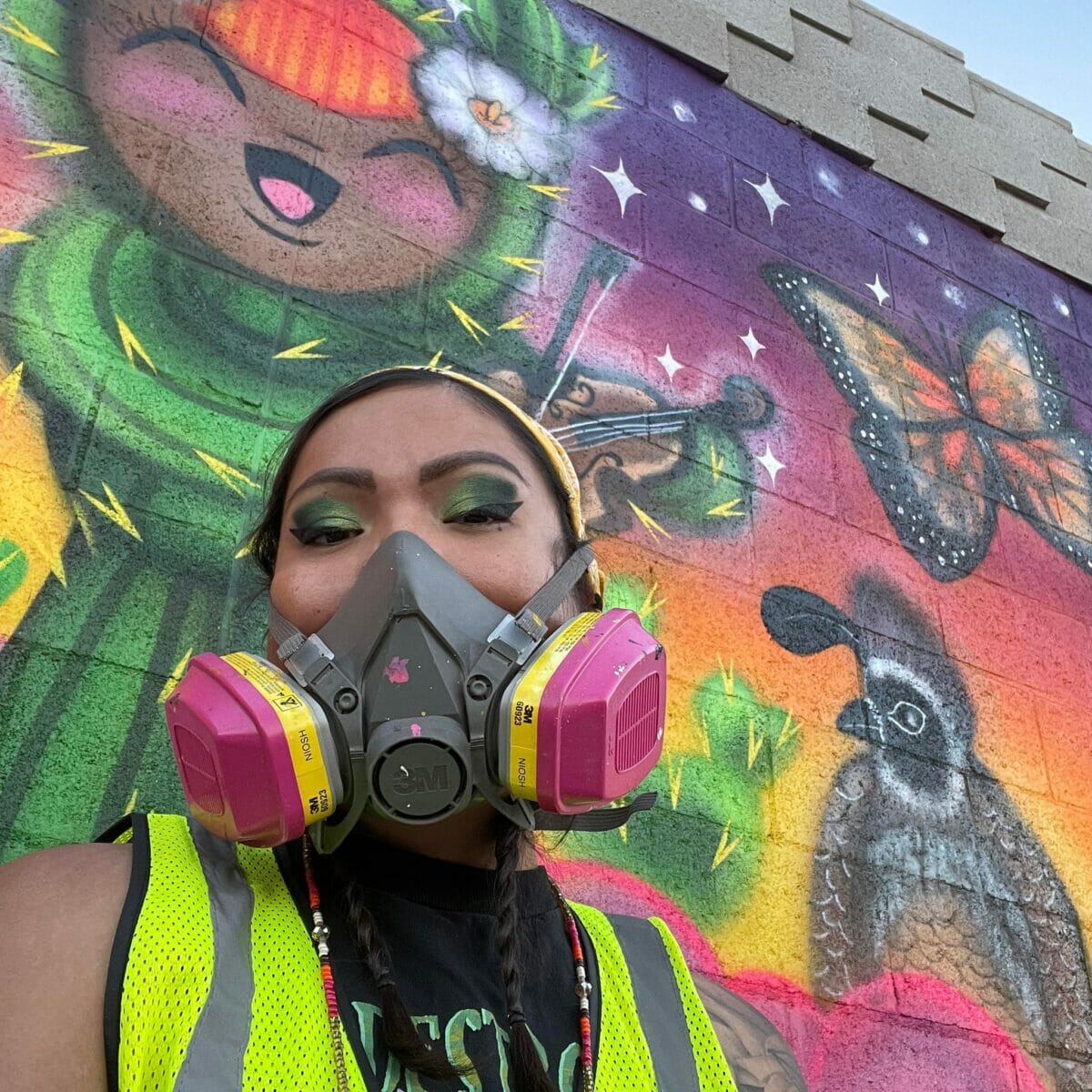 Mujer artista con máscara protectora pinta mural sobre animales