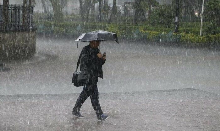 persona camina con paraguas bajo lluvia intensa 