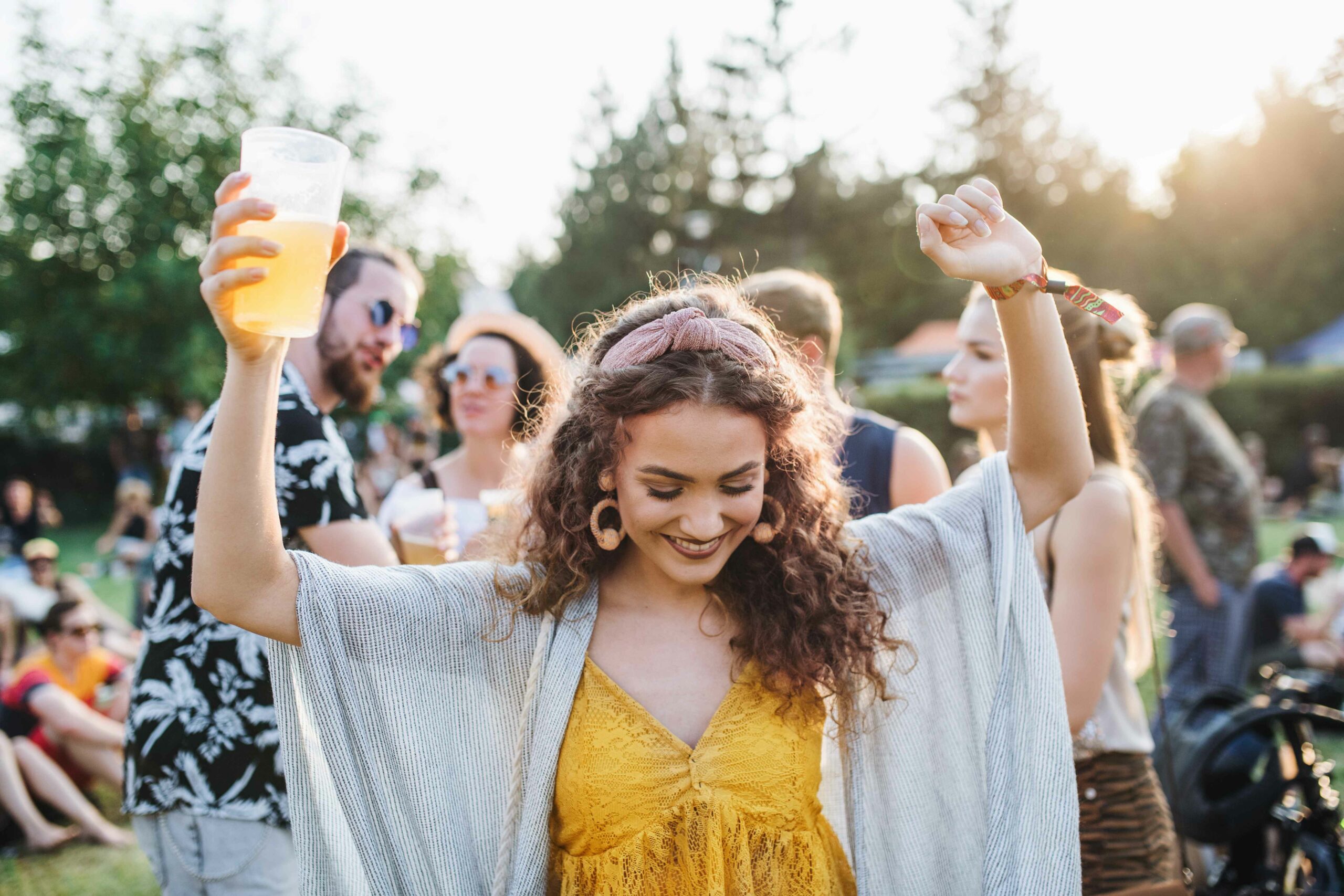 Chica en festival de música con bebida en la mano.