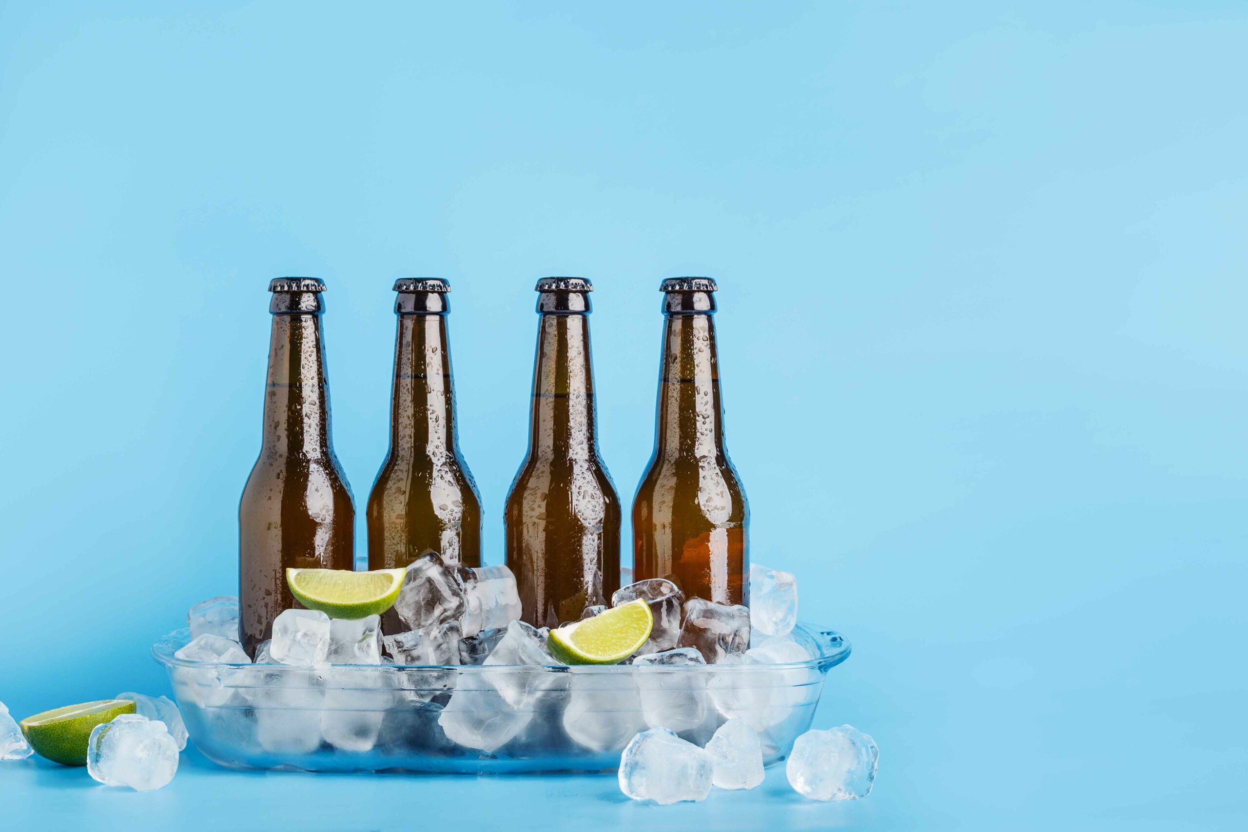 Botellas de cerveza con hielo y unos trozos de limón.
