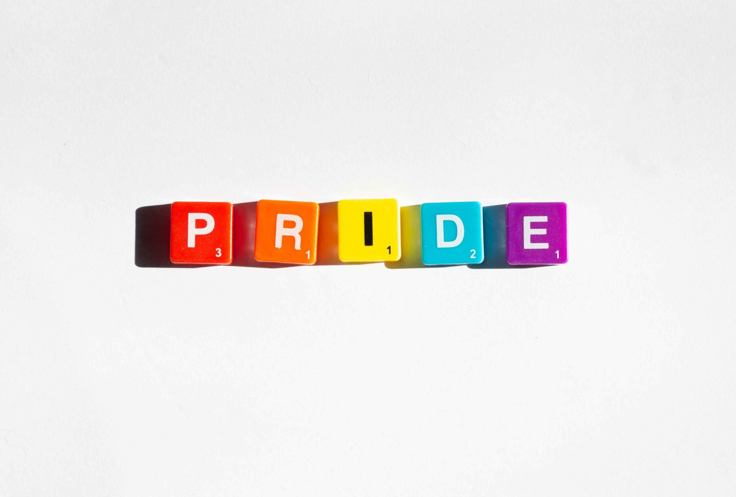 Foto ilustrativa de la palabra pride escrita con fichas de Scrabble con los colores de la bandera.