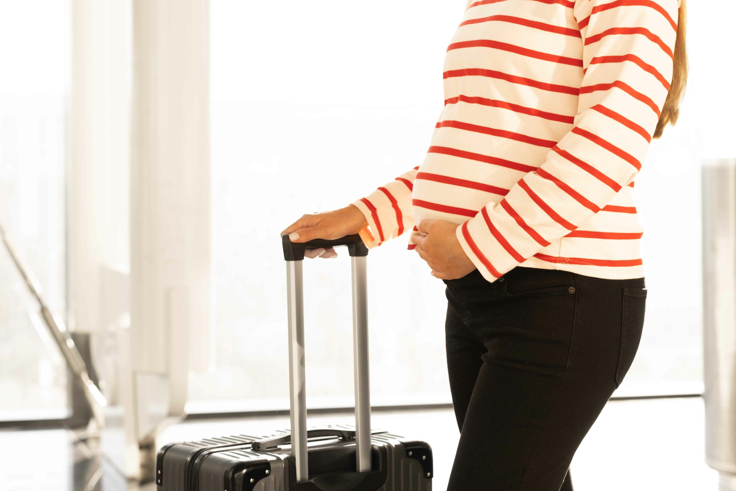 Foto ilustrativa de mujer embarazada con maleta en aeropuerto.