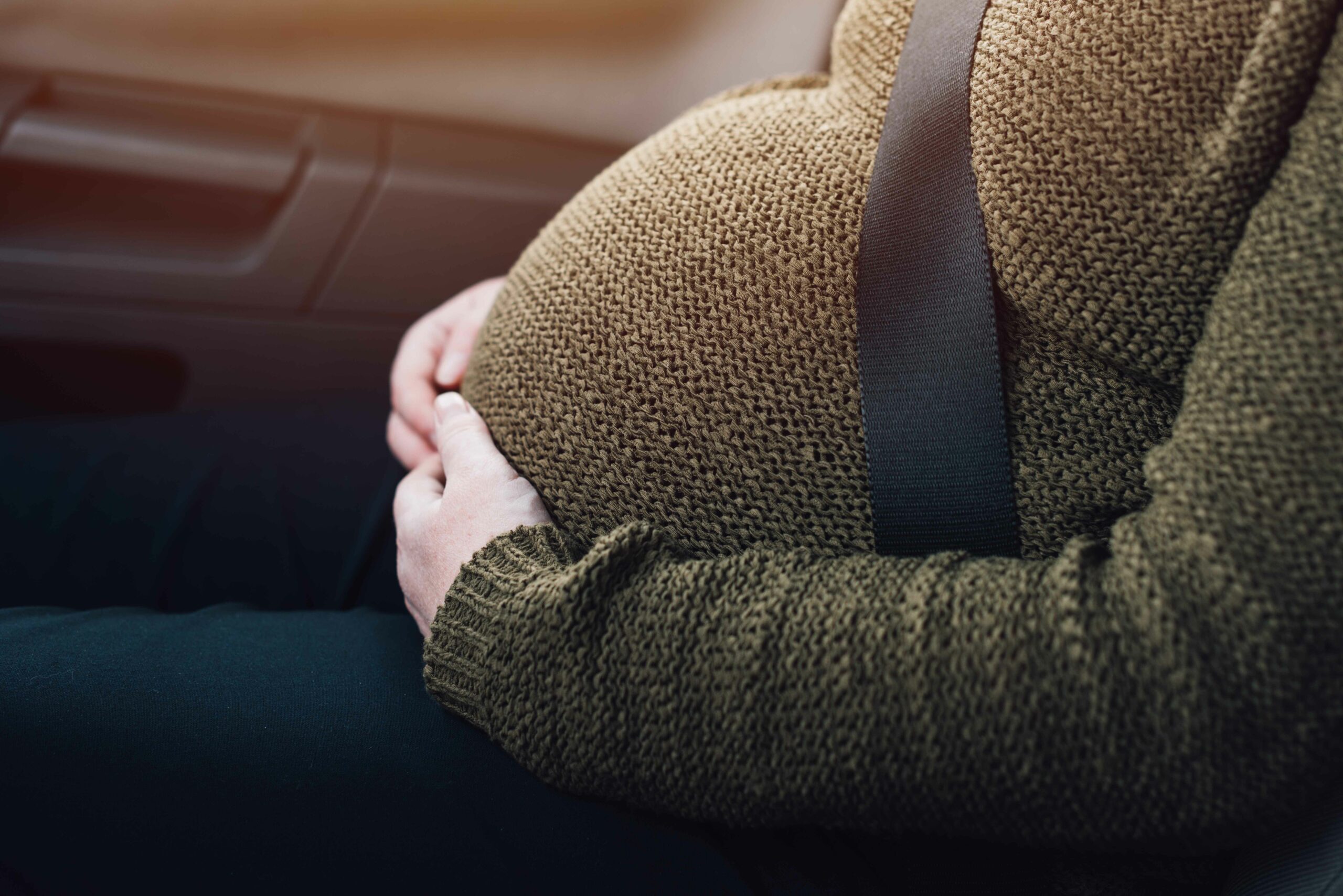 Foto ilustrativa de mujer embaraza en automovuil con cinturón de seguridad.