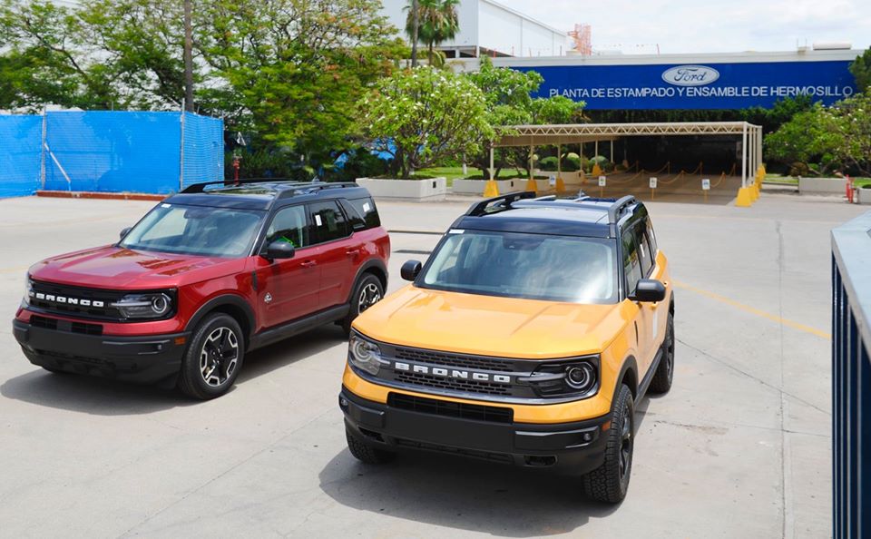 Dos autos Bronco, uno rojo y uno amarillo estacionados en la entrada de Ford Hermosillo